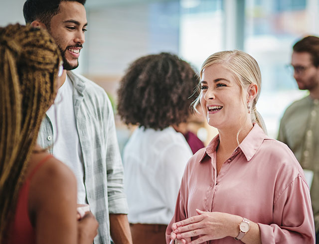 two women and a man smiling and talking in a circle