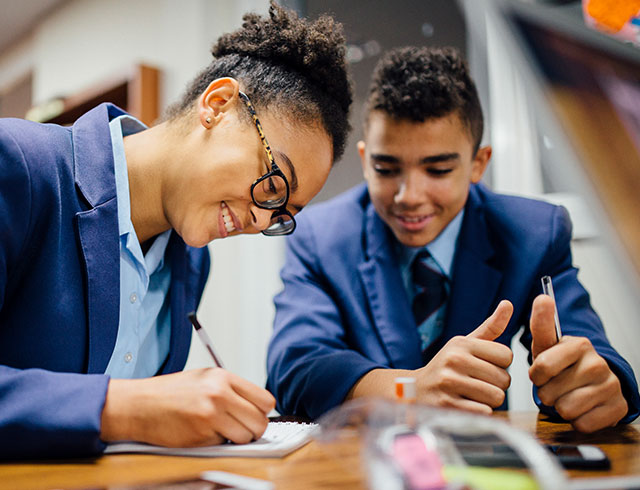 two students in uniforms working together