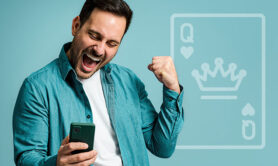 man looking at his phone while smiling and raising his arm in the air