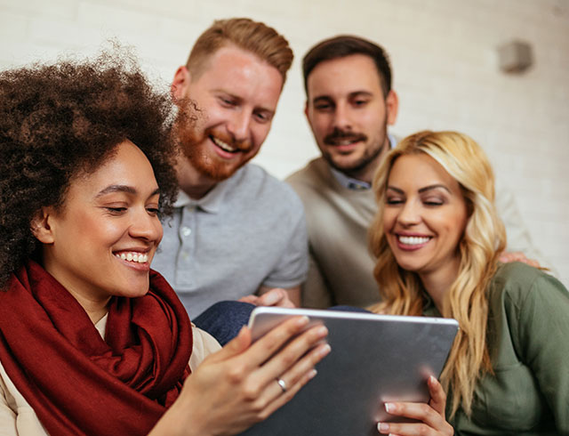 two men and two women smiling at a tablet