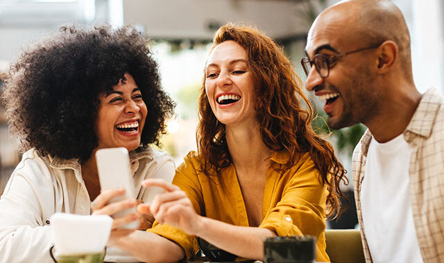 group of friends laughing and looking at a phone and laughing