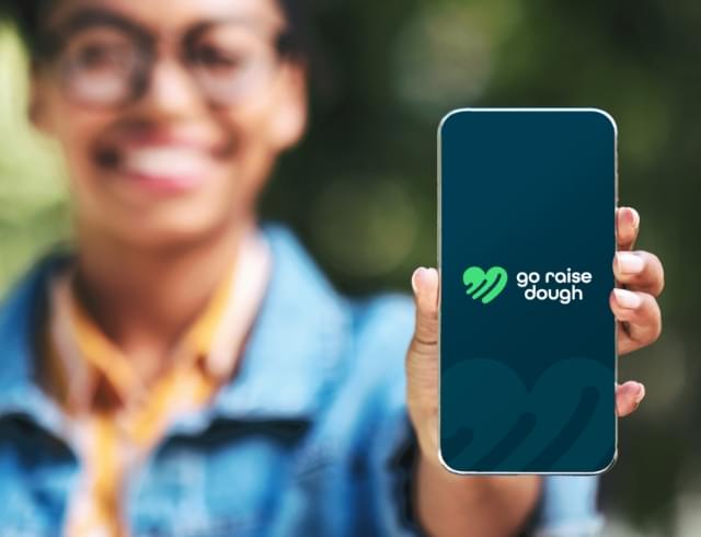 student holding up their phone featuring the Go Raise Dough logo on the screen