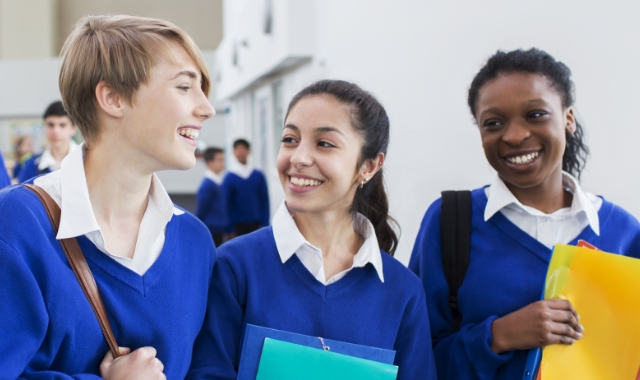 three students discussing walking down the hallway at school and talking