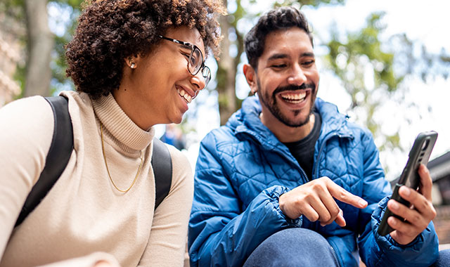 man and woman looking at a phone and smiling